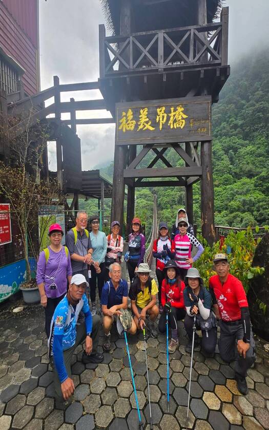 山海戀單車車友與全長約175公尺的福美吊橋合影，福美吊橋宛如一道優美的弧線橫跨山谷。